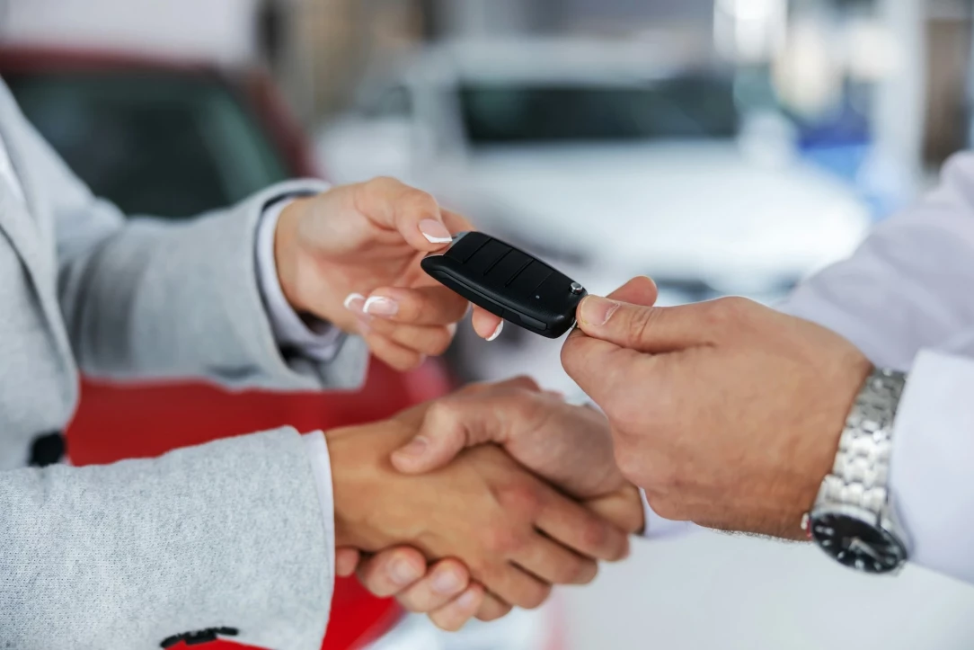 propietario de coche nuevo que recibe las llaves de un vendedor